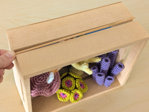 suspending an amigurumi fish in a diorama with fishing line tied to a bamboo skewer
