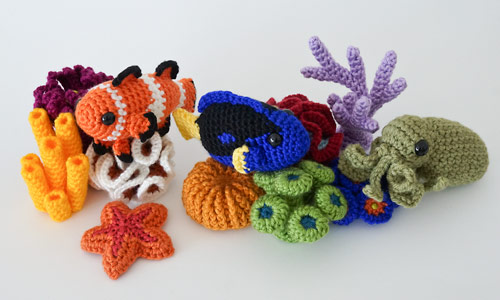 crocheted corals with amigurumi fish, octopus and starfish on a white background